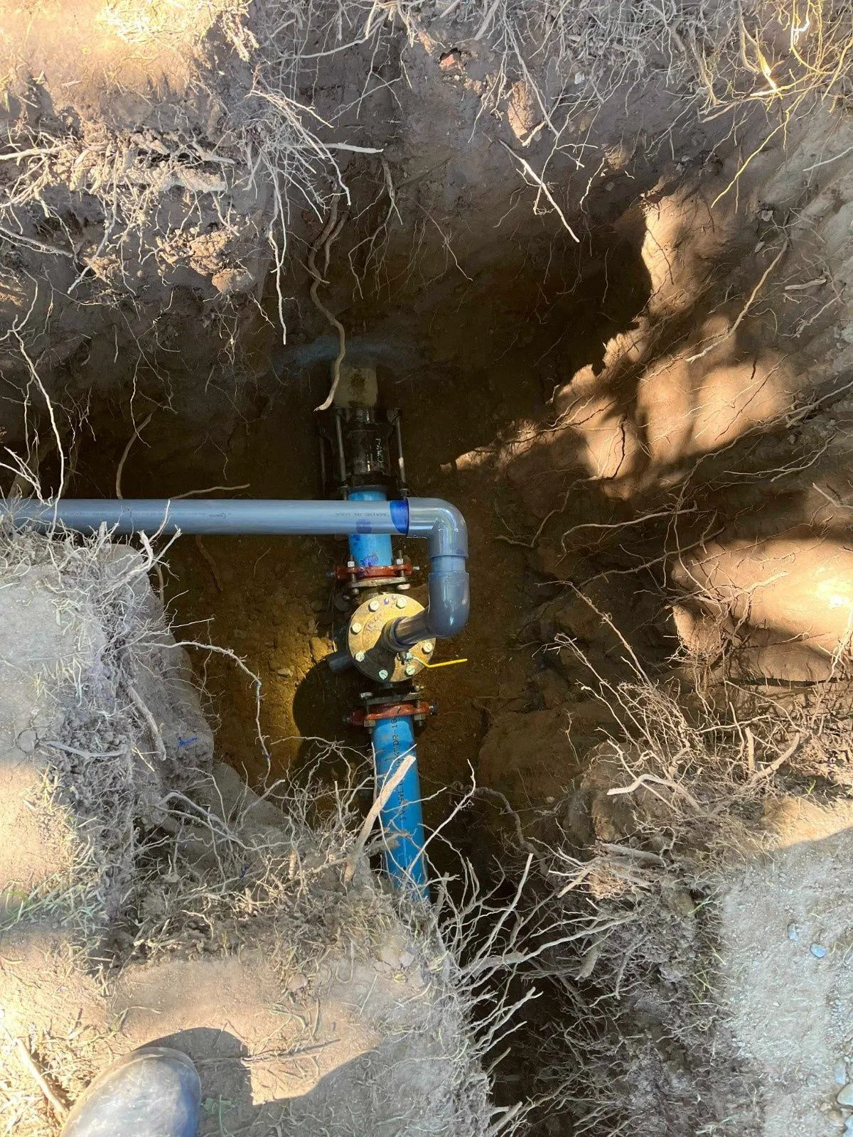 Underground plumbing repair with exposed piping in a trench